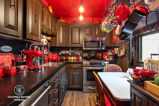 kitchen featuring appliances with stainless steel finishes, dark brown cabinets, and light wood-type flooring