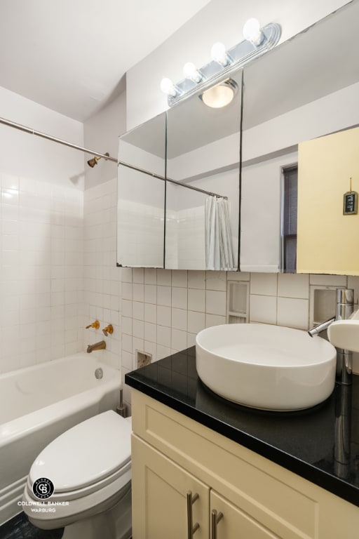 full bathroom with decorative backsplash, sink, toilet, and shower / bath combo with shower curtain