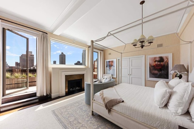 bedroom with visible vents, an inviting chandelier, a fireplace with raised hearth, crown molding, and a view of city