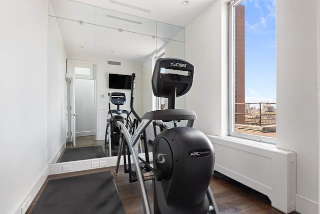 exercise room with visible vents, dark wood-type flooring, and baseboards