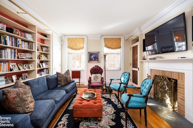 sitting room with a brick fireplace, crown molding, and hardwood / wood-style floors