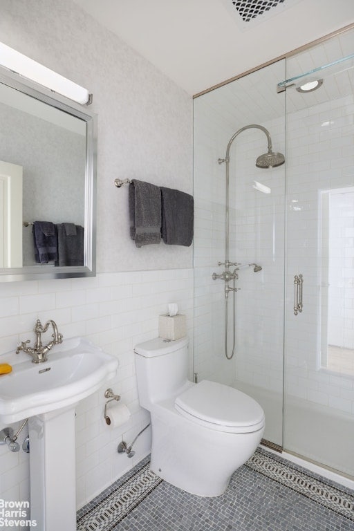 bathroom with tile walls, toilet, walk in shower, and tile patterned flooring