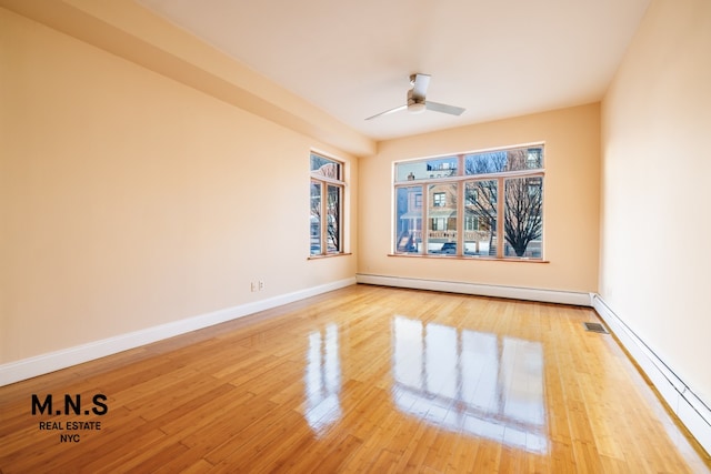 unfurnished room with ceiling fan, wood-type flooring, and a baseboard heating unit