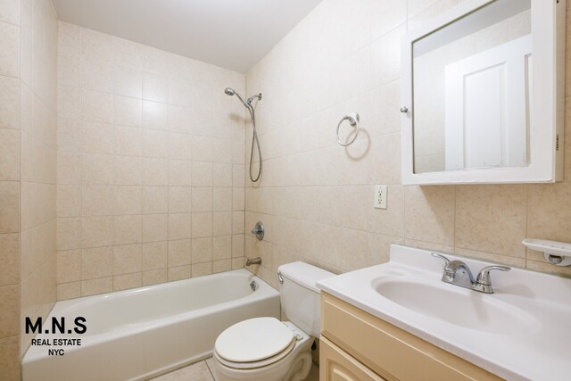 full bathroom with tiled shower / bath combo, vanity, tile walls, and toilet