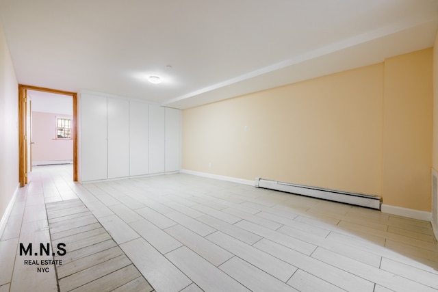 empty room featuring a baseboard radiator, light wood-style flooring, and baseboards