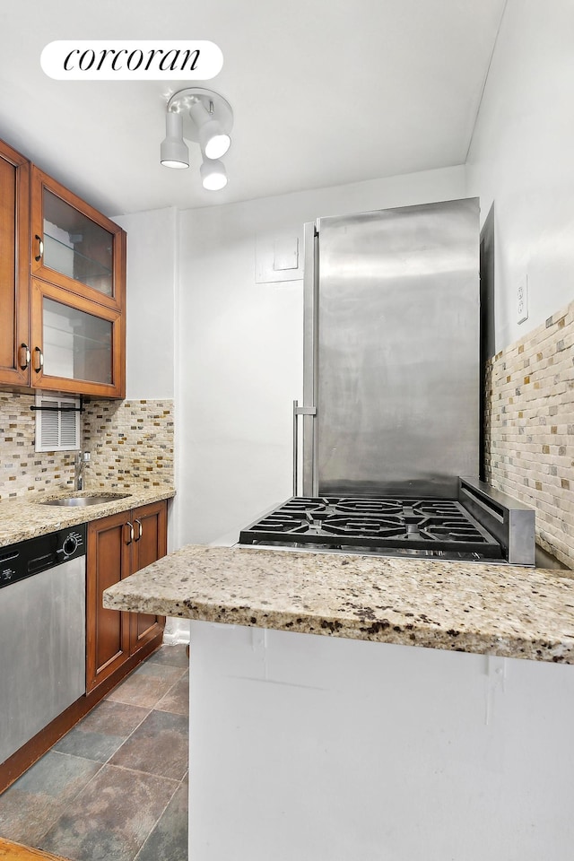240 E 76th St Unit 1U, New York City, NY 10021 - kitchen with stainless steel appliances, brown cabinetry, a sink, and decorative backsplash