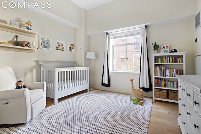 bedroom featuring a crib and light hardwood / wood-style flooring