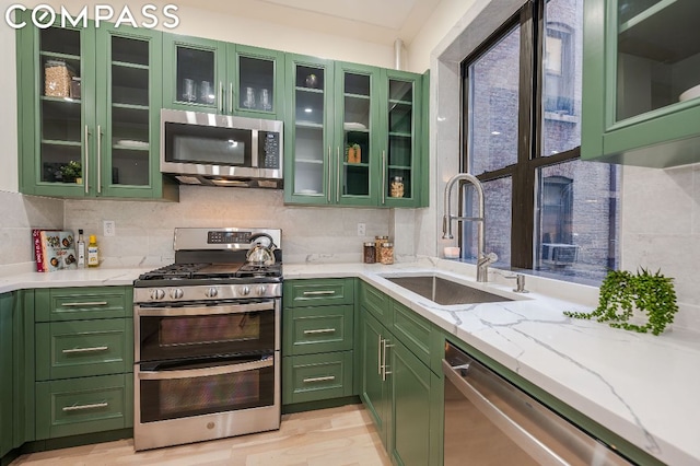 kitchen featuring light stone countertops, green cabinets, appliances with stainless steel finishes, and sink