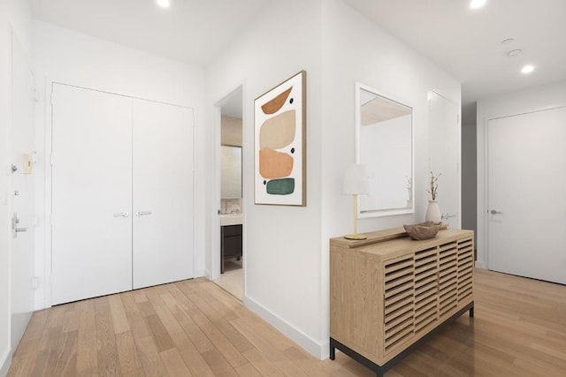 hall featuring light wood finished floors, baseboards, and recessed lighting