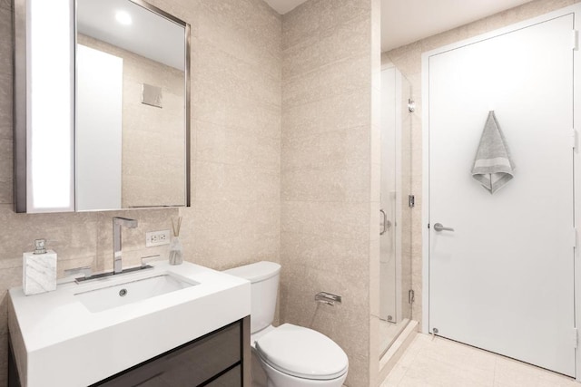 full bath with toilet, vanity, tile walls, a shower stall, and tile patterned floors