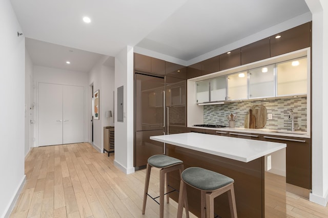kitchen featuring a sink, a kitchen bar, modern cabinets, light wood-style floors, and light countertops