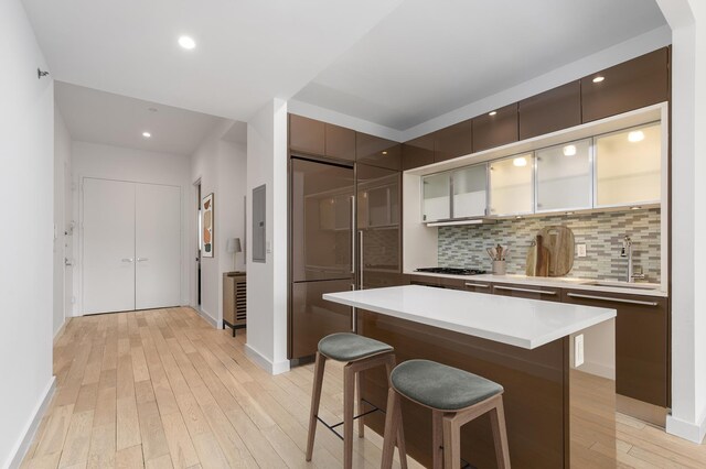 75 Wall St Unit 31P, New York City, NY 10005 - kitchen featuring built in fridge, a sink, a breakfast bar, light wood-type flooring, and light countertops