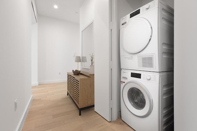 clothes washing area with recessed lighting, stacked washer and clothes dryer, baseboards, and light wood finished floors