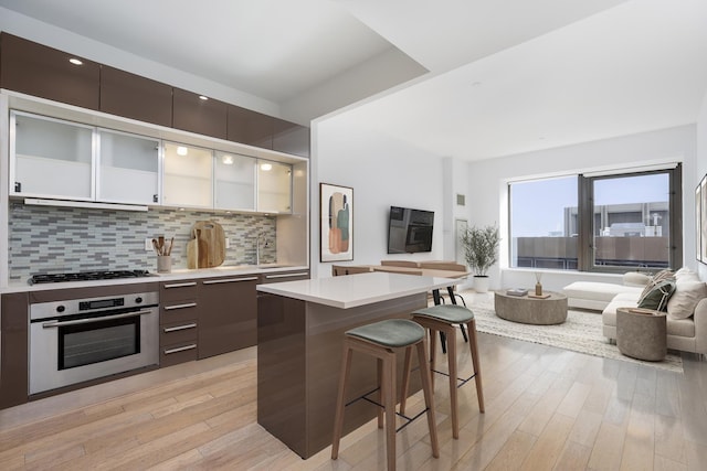 kitchen featuring stainless steel oven, a kitchen breakfast bar, light countertops, and modern cabinets