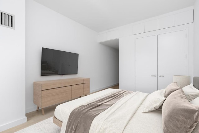 bedroom featuring baseboards, a closet, visible vents, and light wood-style floors