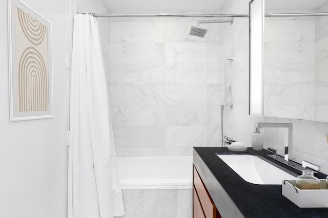 bathroom featuring tiled shower / bath combo, vanity, and decorative backsplash