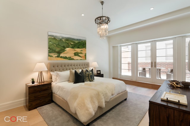 bedroom with light hardwood / wood-style floors, french doors, and a chandelier