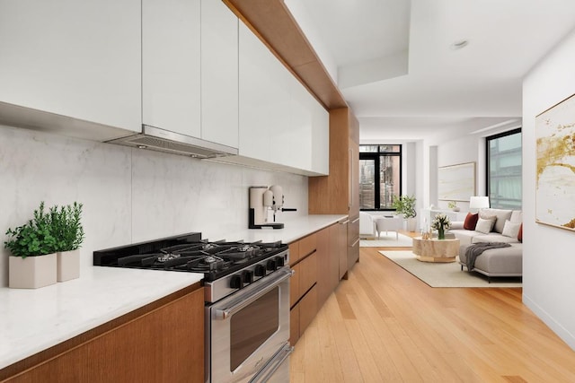 kitchen featuring white cabinetry, light wood-type flooring, tasteful backsplash, and stainless steel gas range oven