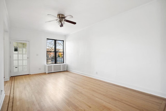 spare room with ceiling fan, radiator heating unit, and light wood-type flooring