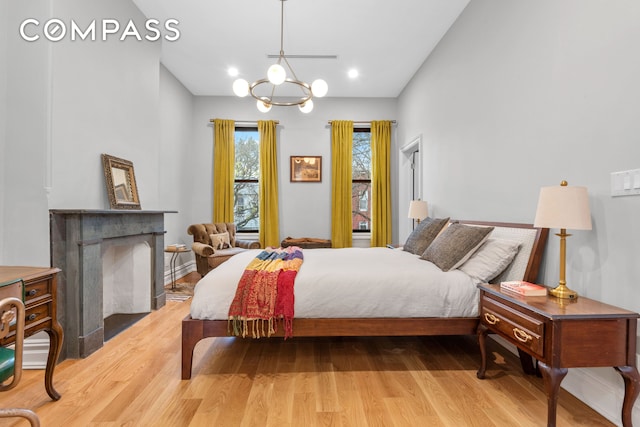 bedroom featuring wood finished floors, a chandelier, and a fireplace