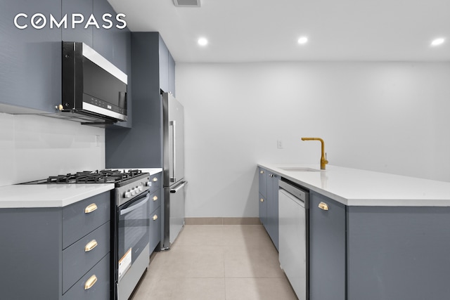 kitchen featuring stainless steel appliances, a sink, light tile patterned floors, recessed lighting, and gray cabinetry