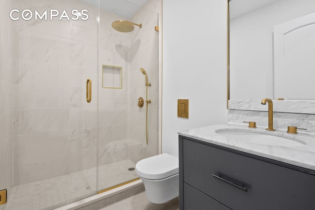 bathroom featuring toilet, vanity, and a stall shower