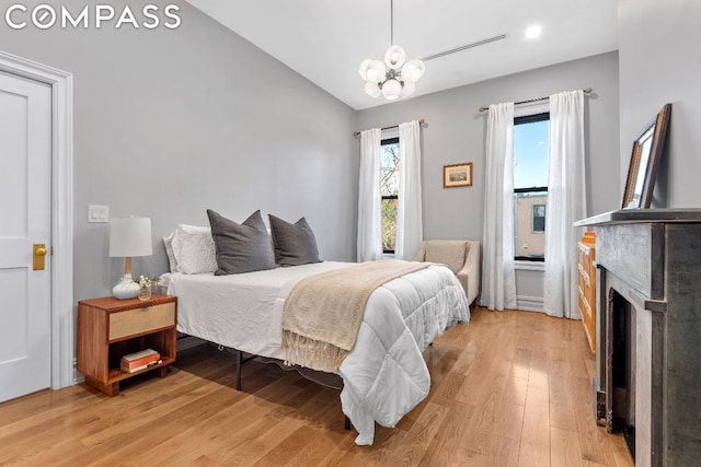 bedroom featuring an inviting chandelier, lofted ceiling, and wood-type flooring