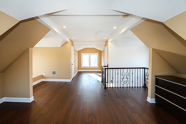 bonus room with vaulted ceiling with beams and dark wood-type flooring