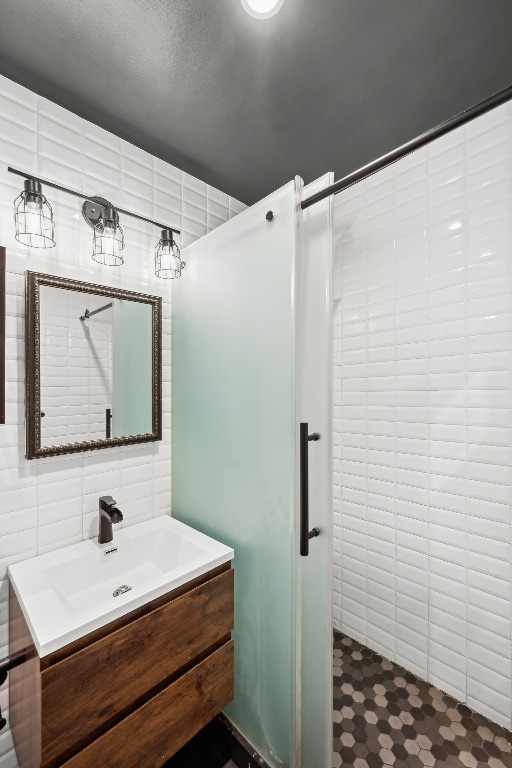 bathroom with a textured ceiling, tile walls, walk in shower, and vanity