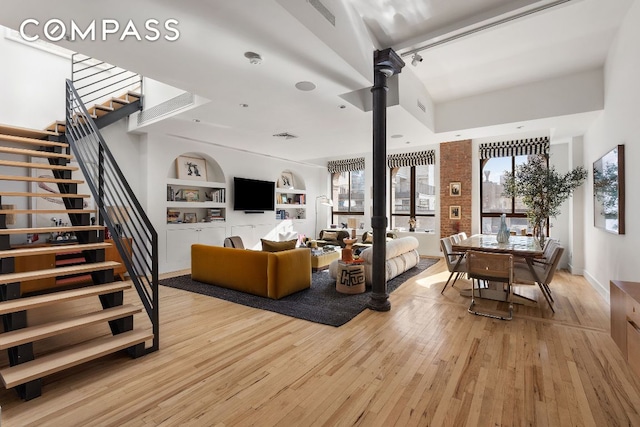 living room with built in shelves and light hardwood / wood-style floors