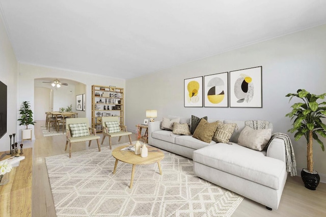 living area featuring arched walkways, wood finished floors, and a ceiling fan