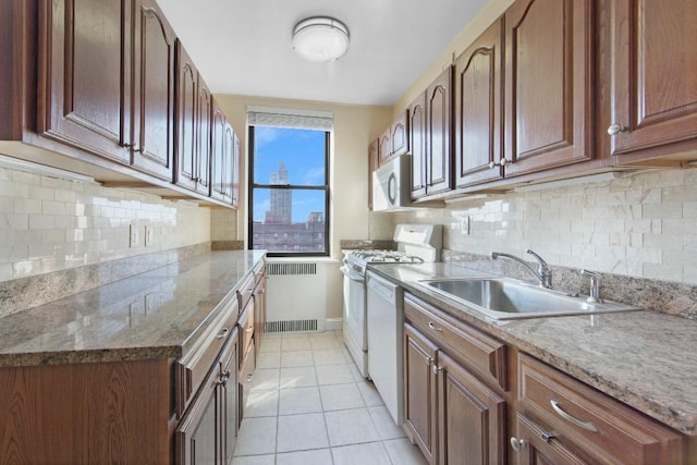 kitchen featuring light tile patterned floors, decorative backsplash, white appliances, radiator, and sink