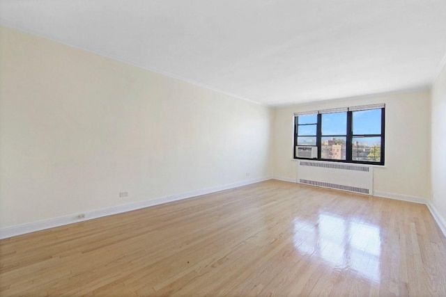 spare room with radiator heating unit and light hardwood / wood-style flooring