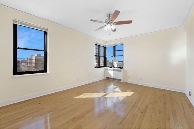 spare room with ceiling fan, cooling unit, light hardwood / wood-style flooring, and radiator heating unit