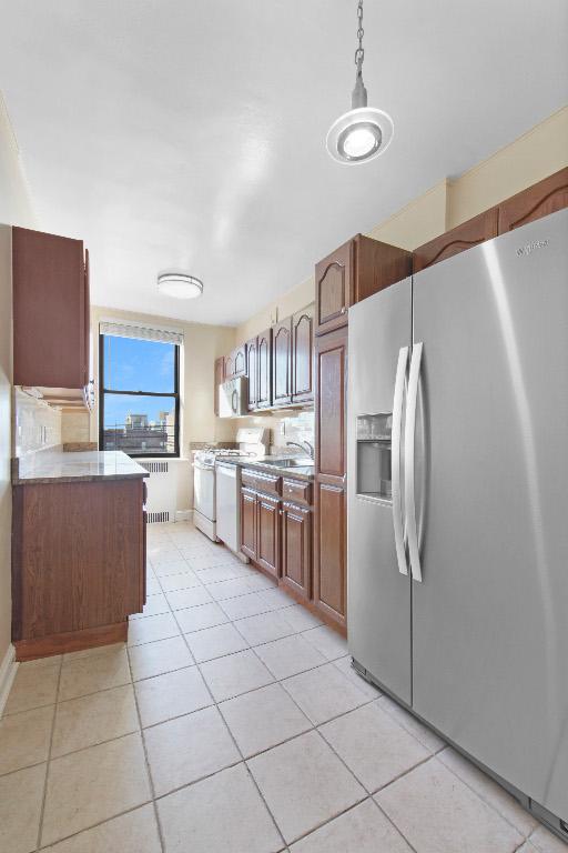 kitchen featuring stainless steel refrigerator with ice dispenser, decorative light fixtures, white stove, sink, and light tile patterned flooring