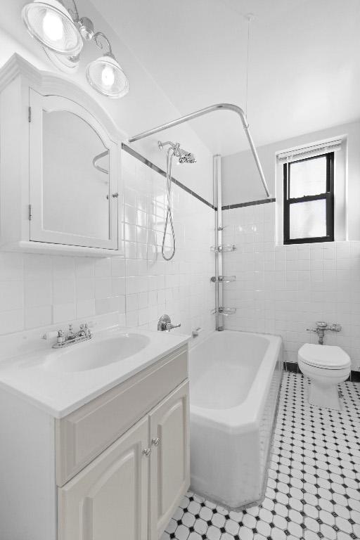 full bathroom with toilet, vanity, tile walls, and  shower combination