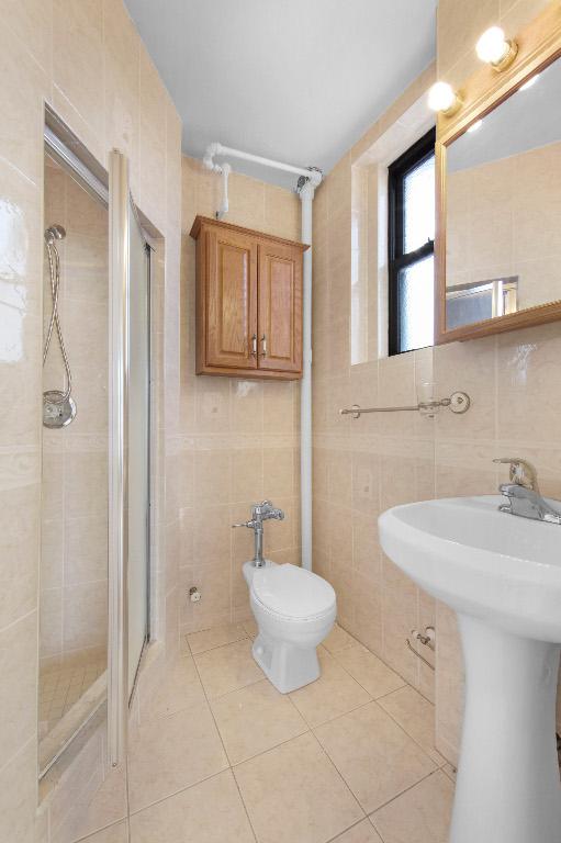 bathroom featuring tile walls, tile patterned floors, walk in shower, and sink