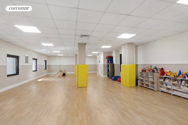 interior space featuring a paneled ceiling, wood finished floors, visible vents, and baseboards