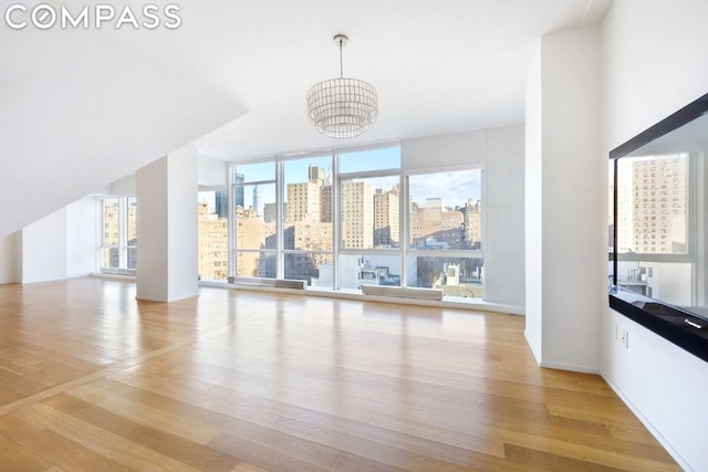 living room featuring a notable chandelier, light wood-style flooring, a view of city, and expansive windows