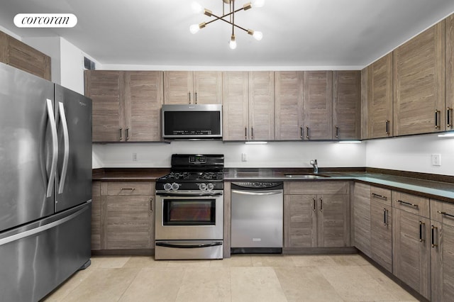 kitchen featuring visible vents, dark countertops, appliances with stainless steel finishes, a chandelier, and a sink