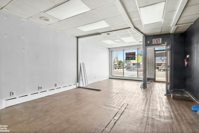 unfurnished room featuring hardwood / wood-style flooring, a baseboard radiator, and a paneled ceiling