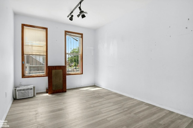 unfurnished room featuring track lighting, an AC wall unit, and light wood-type flooring