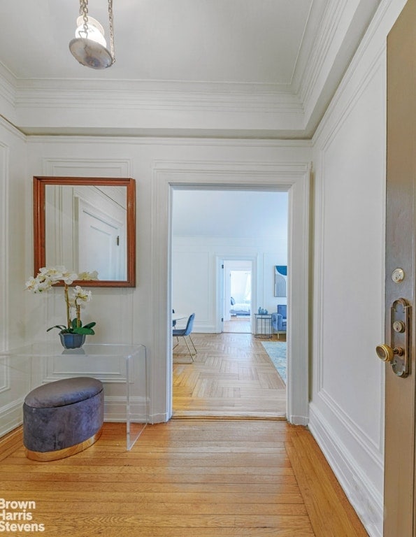 hall with ornamental molding and light hardwood / wood-style floors