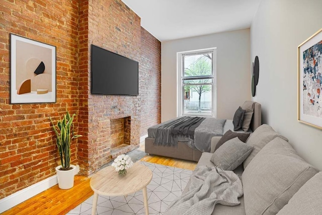 bedroom with light hardwood / wood-style floors, brick wall, and a brick fireplace