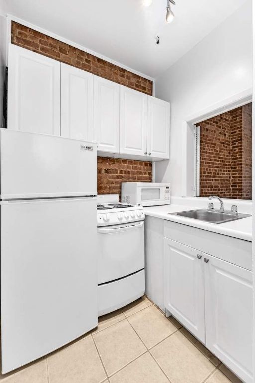 kitchen featuring light tile patterned floors, sink, white appliances, and white cabinets