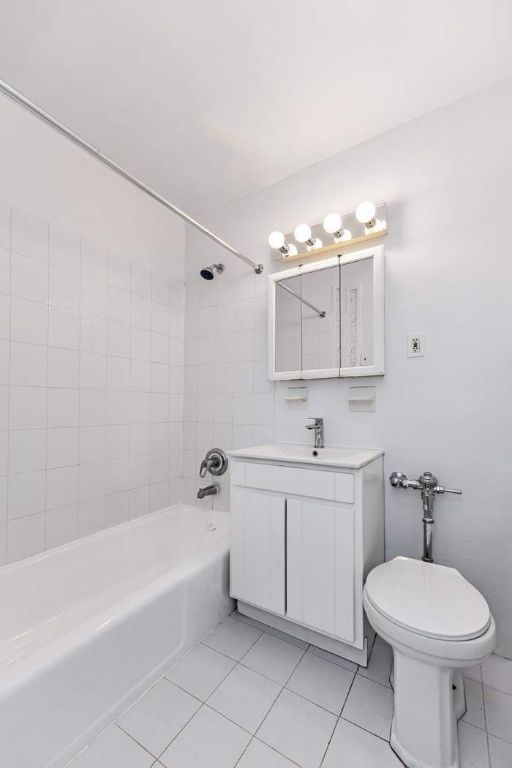 full bathroom with toilet, tiled shower / bath, tile patterned floors, and vanity