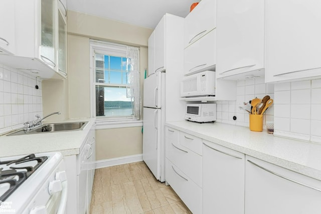 kitchen featuring plenty of natural light, white cabinetry, tasteful backsplash, and white appliances