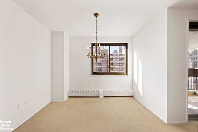 carpeted empty room featuring baseboard heating and a notable chandelier