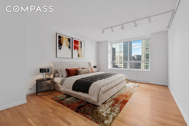 bedroom featuring track lighting, baseboards, and wood finished floors