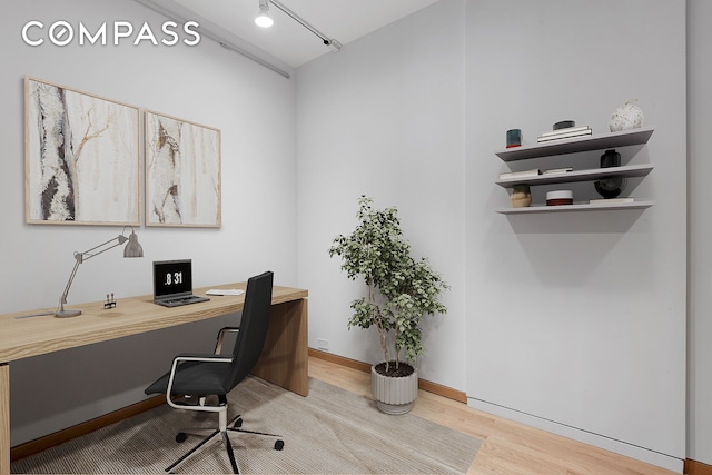 home office with track lighting and wood finished floors